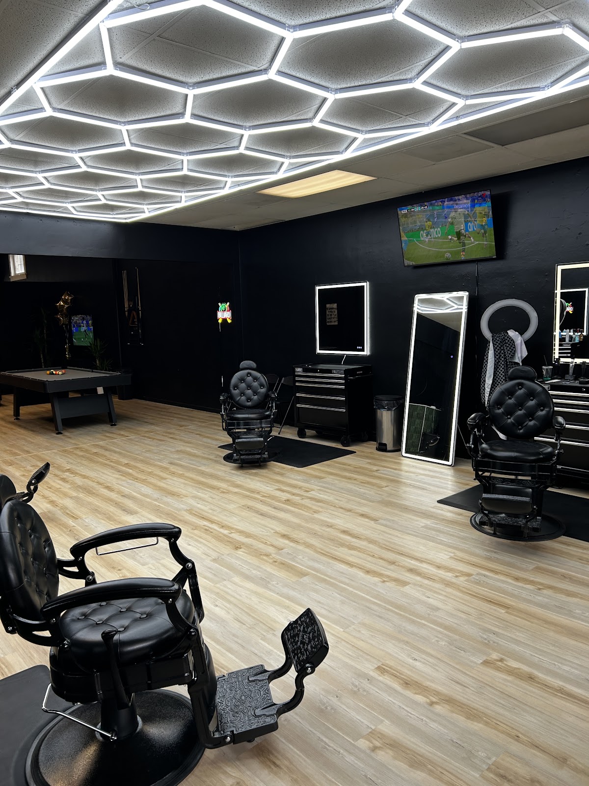 Luxo’s black barber chairs beneath geometric ceiling lights on Cole Street