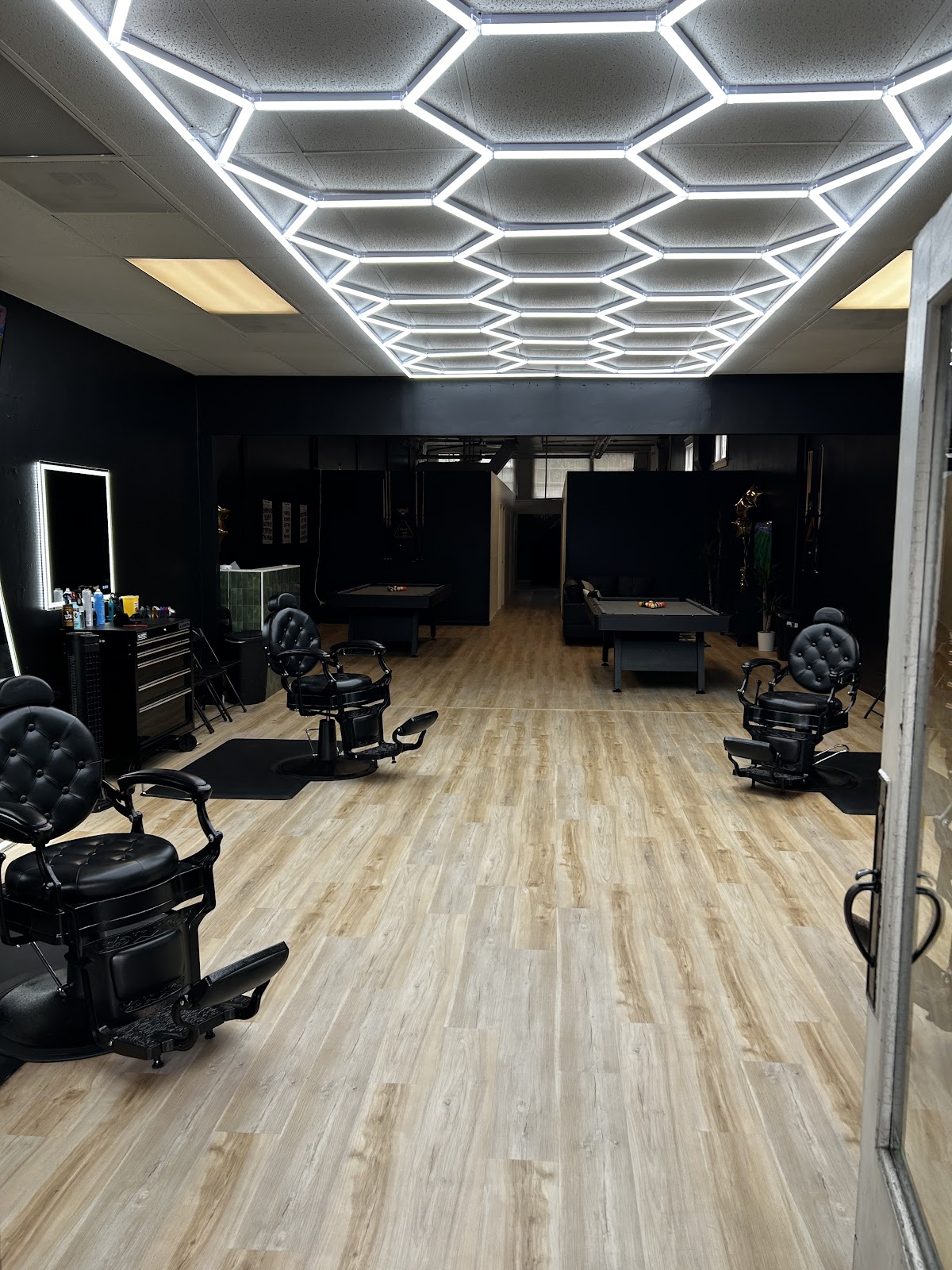 The view into Luxo from the entrance, with black barber chairs and illuminated mirrors