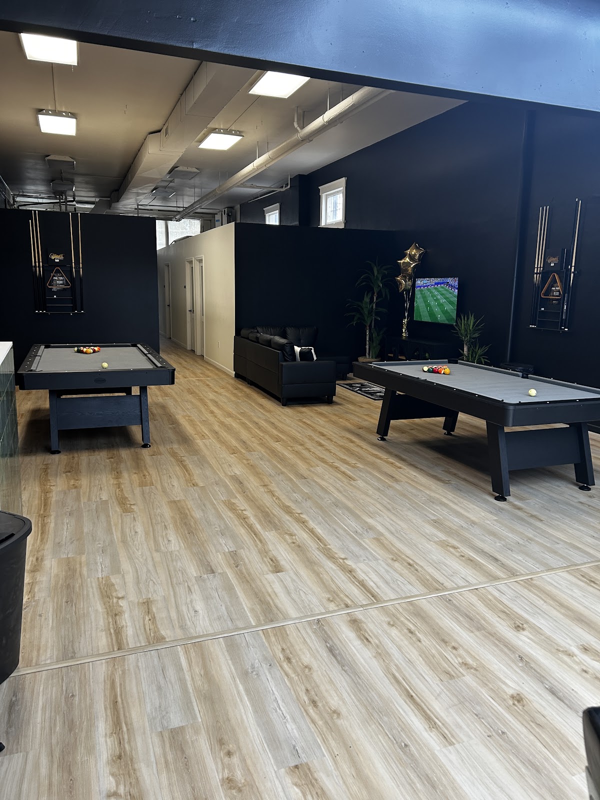 Pool tables and wood floors in the lounge at Luxo Barbershop